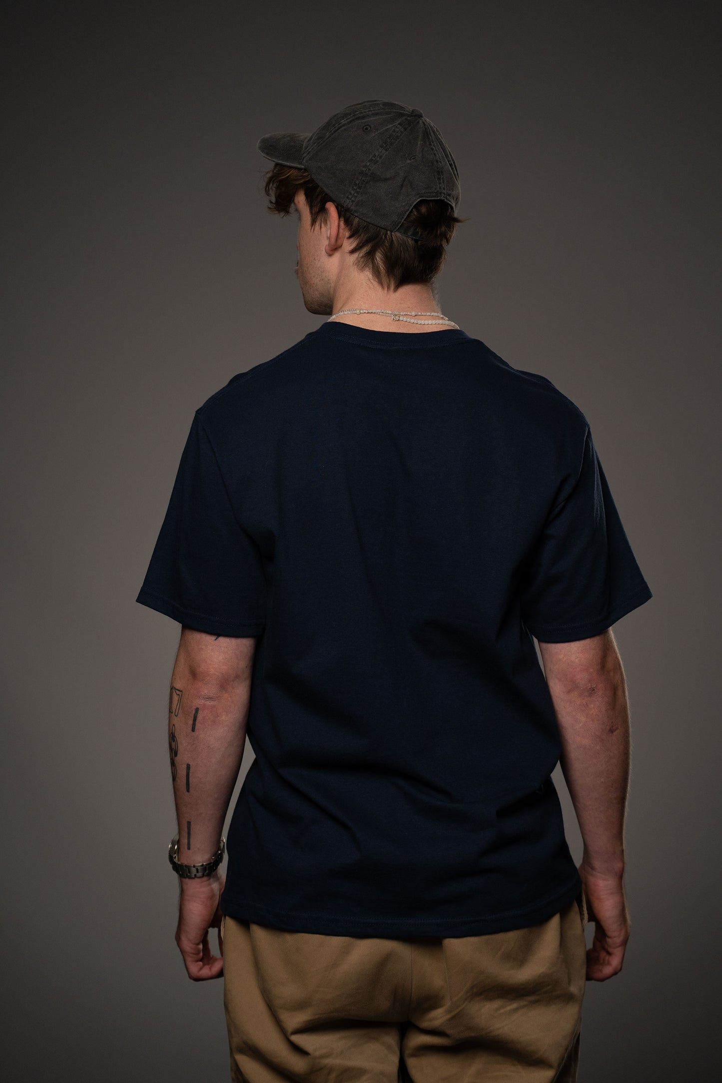 Rückansicht eines dunkelblauen T-Shirts ohne Aufdruck. Die glatte Stofffläche zeigt die schlichte Verarbeitung des Rückenteils.