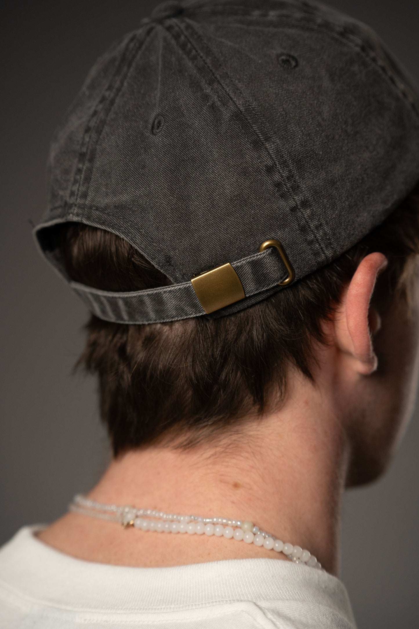 Rückansicht einer schwarzen Cap mit verstellbarem Riemen und Metallschnalle in Messingoptik. Der Stoff zeigt eine dezente Vintage-Waschung.