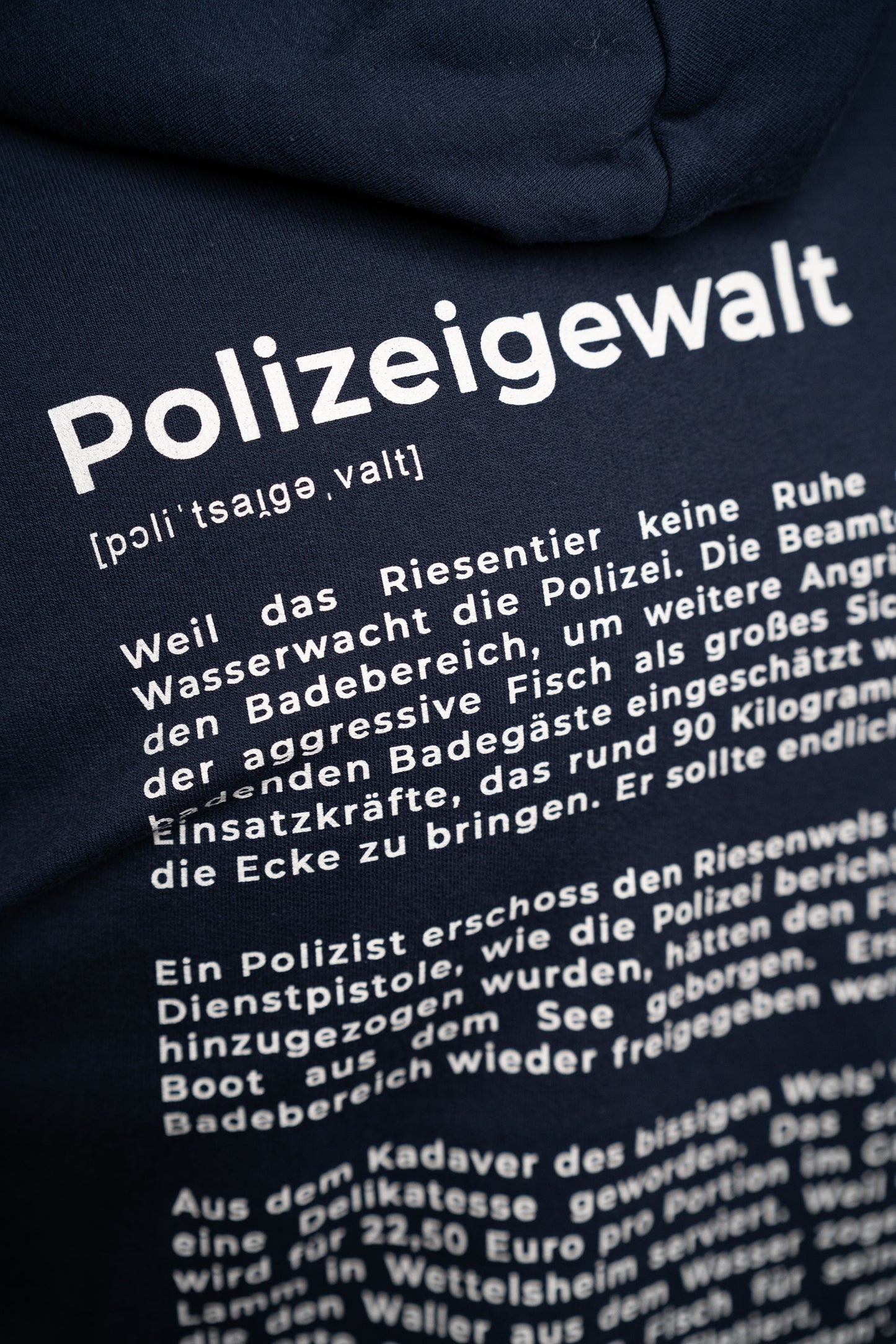 Nahaufnahme des Rückendrucks: das Wort „Polizeigewalt“ in großen weißen Buchstaben mit Lautschrift, darunter beginnt der satirische Textabschnitt in kleinerer Typografie.