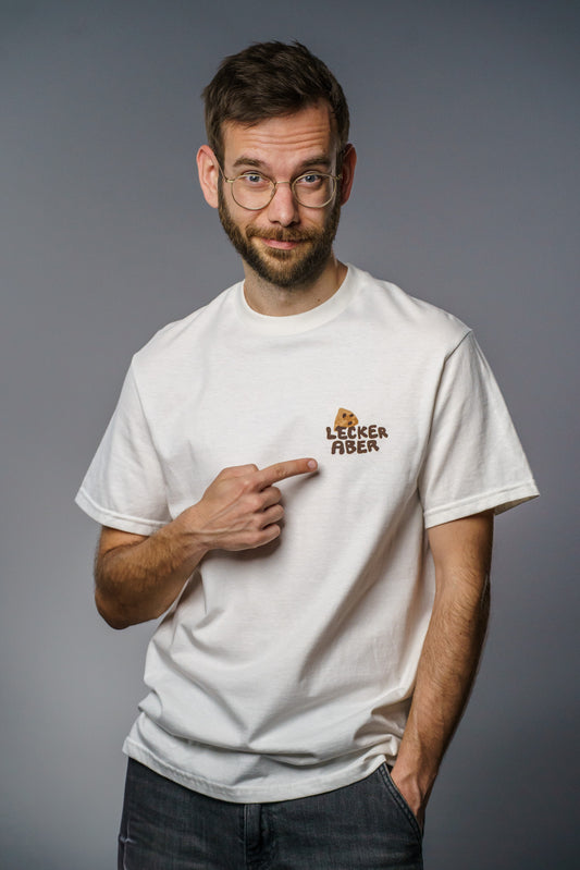 Weißes T-Shirt mit kleinem Frontprint auf der linken Brustseite. Der Druck zeigt ein gezeichnetes Keksstück über dem braunen Schriftzug „LECKER ABER“ in handschriftlich wirkender Blockschrift. Das Shirt hat eine klassische Passform mit Rundhalsausschnitt und kurzen Ärmeln  schlicht, aber mit augenzwinkernder Aussage.
